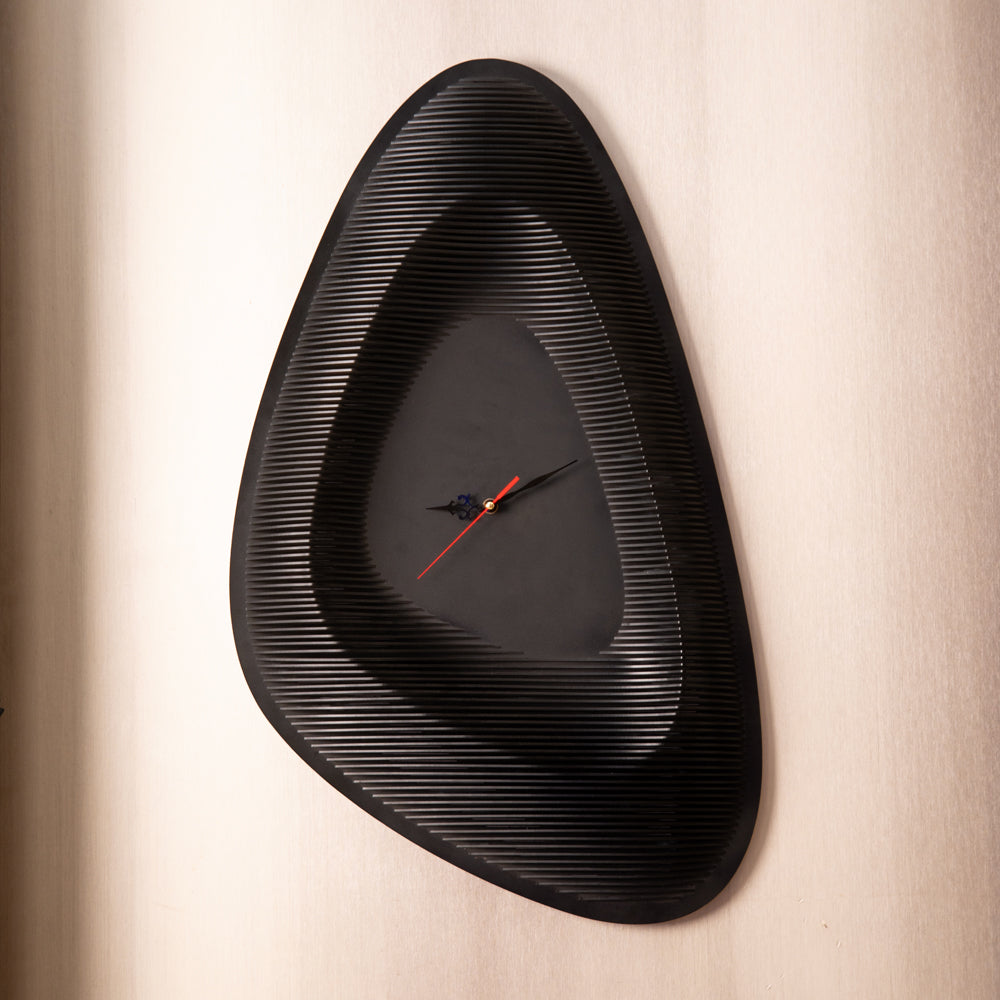 Black wall clock with a unique design on a beige wall
