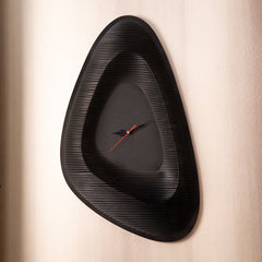 Black wall clock with a unique design on a beige wall