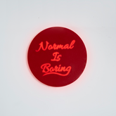 Front shot of wall hanging displaying “Normal Is Boring” text clearly