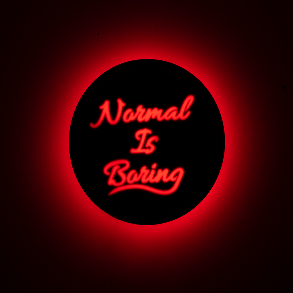 Front shot of wall hanging displaying “Normal Is Boring” text clearly